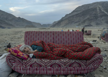 An Afghan refugee rests in the desert next to a camp near the Torkham Pakistan-Afghanistan border, in Torkham, Afghanistan, Friday, Nov. 17, 2023. A huge number of Afghans refugees entered the Torkham border to return home hours before the expiration of a Pakistani government deadline for those who are in the country illegally to leave or face deportation. (AP Photo/Ebrahim Noroozi)