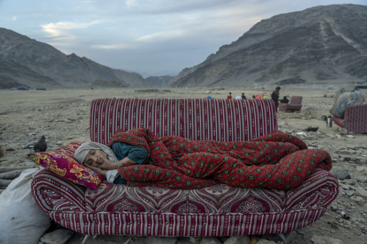 An Afghan refugee rests in the desert next to a camp near the Torkham Pakistan-Afghanistan border, in Torkham, Afghanistan, Friday, Nov. 17, 2023. A huge number of Afghans refugees entered the Torkham border to return home hours before the expiration of a Pakistani government deadline for those who are in the country illegally to leave or face deportation. (AP Photo/Ebrahim Noroozi)