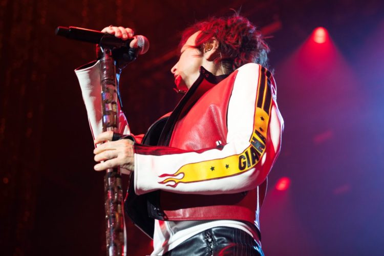 Gianna Nannini infiamma il palco con la sua energia rock e il pugno alzato tra fumo e luci blu. Ph. Luisa Carcavale