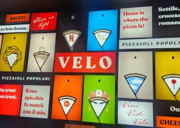 La parete luminosa di Velo con slogan, icone e reinterpretazioni grafiche dello spicchio