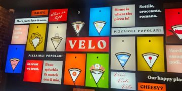 La parete luminosa di Velo con slogan, icone e reinterpretazioni grafiche dello spicchio