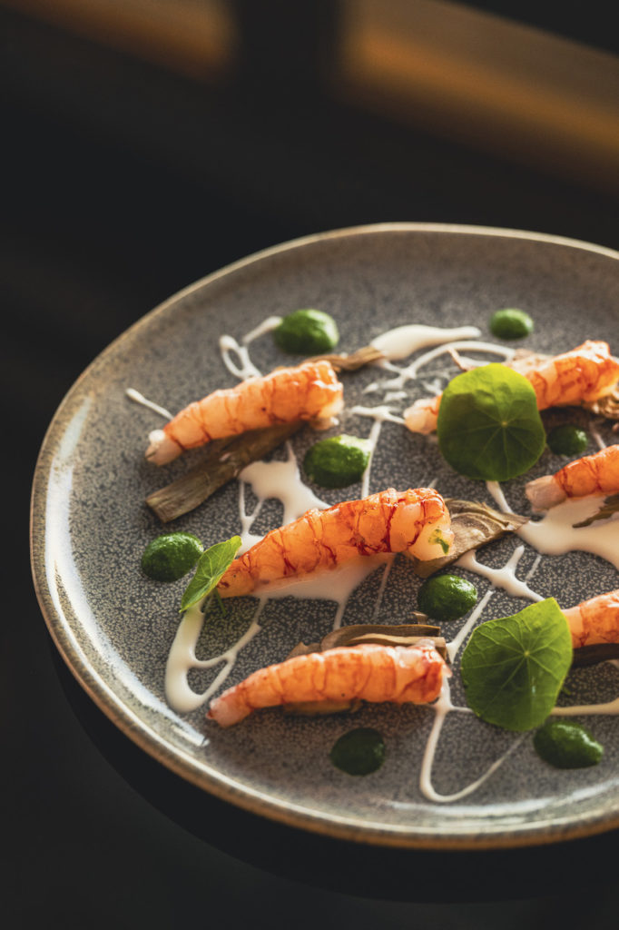 Gambero rosso crudo (o leggermente scottato) servito con crema di latticello o yogurt, salsa verde di erbe e cuori di carciofo